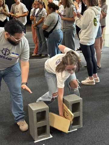 student smashes through a wooden board on cinderblocks 