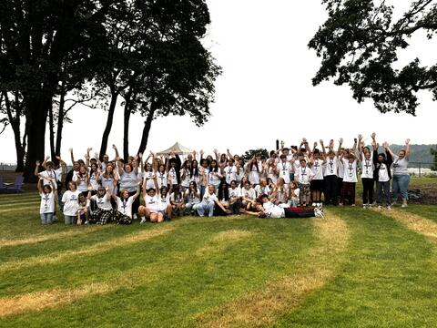 a large group of students and adults raising their hands for a group picture