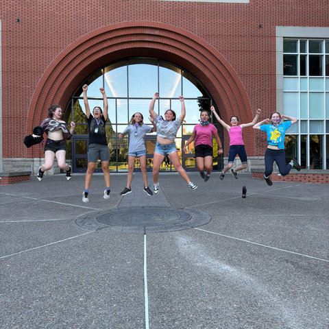 A group of students jumping in front of a building