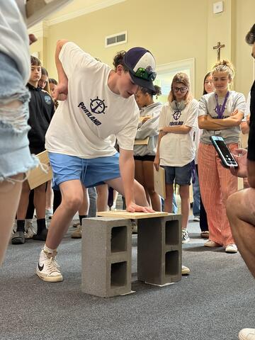 student prepares to smash through a wooden board on cinderblocks 